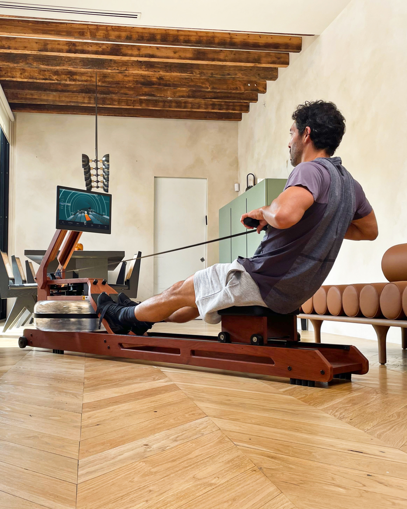 Man rowing in living room with wood flooring and wood ceiling beams